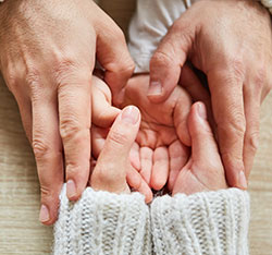Older hands holding younger hands. Links to Gifts of Life Insurance